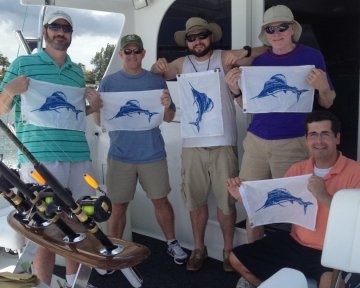 People on boat holding up blue marlin flags